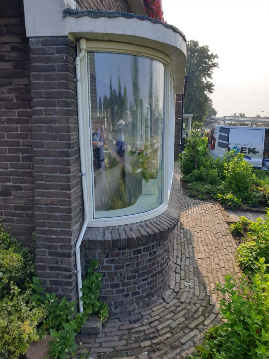 Gebogen erker met witte omlijsting en tuin op de achtergrond
