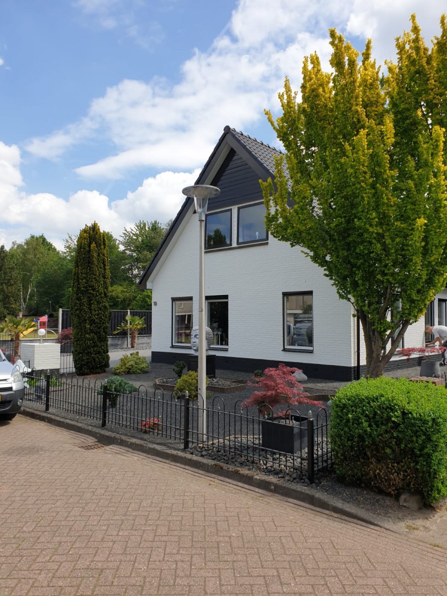 Witte woning met een donkere plint vanaf de straat