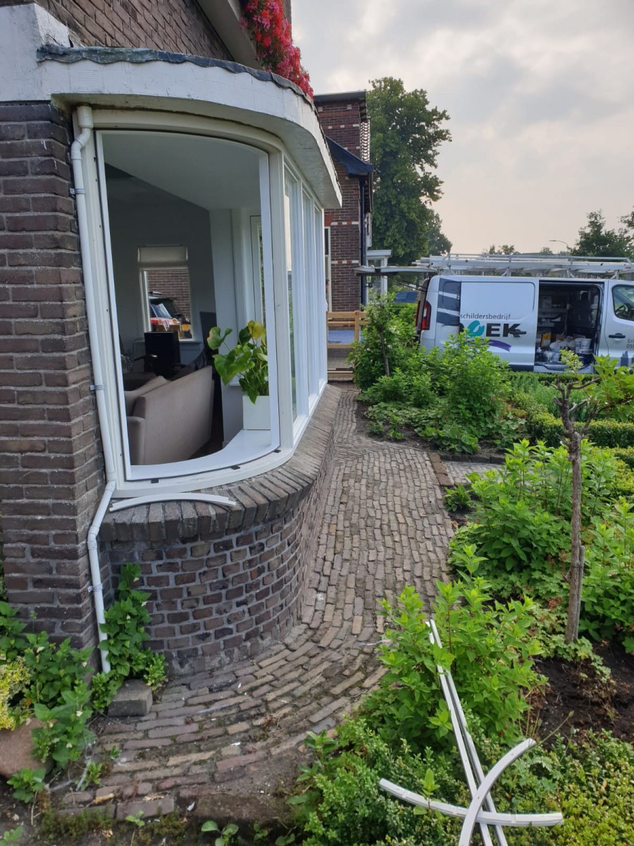 Rondlopende erker met witte kozijnen in een bakstenen gevel